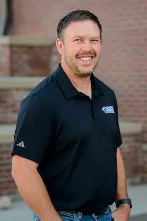 A headshot of Landon Lembitz, Director of Civil Construction at Legacy Construction Group in Cheyenne, Wyoming in front of Cheyenne Frontier Days Headquarters Building